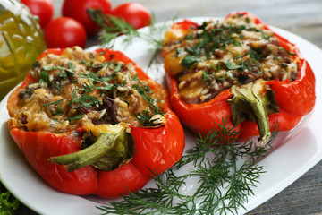 Stuffed red peppers with greens and vegetables on table close