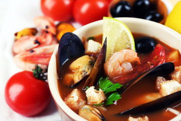Tasty soup with shrimps, mussels, tomatoes and black olives in