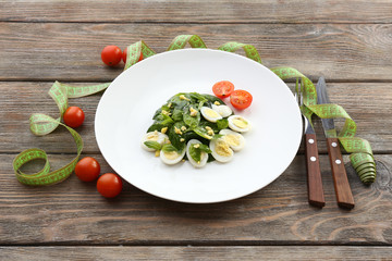 Salad with quail egg and basil in plate with measuring tape