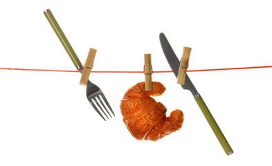 Fork, knife and croissant hanging from clothesline isolated