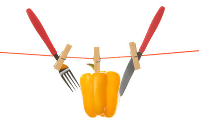 Fork, knife and bell pepper hanging from clothesline isolated