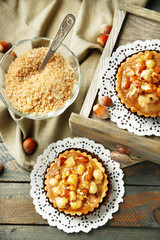 Mini cakes with nuts on napkin on wooden background
