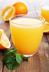 Glasses of orange juice with oranges on wooden table close up