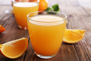 Fototapeta na wymiar Glasses of orange juice with oranges on wooden table close up
