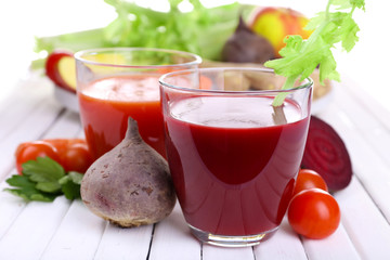 Glasses of beet juice with vegetables on wooden table closeup