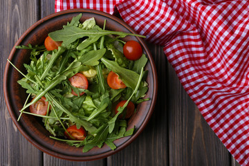 Salad with arugula and cherry tomatoes on wooden table