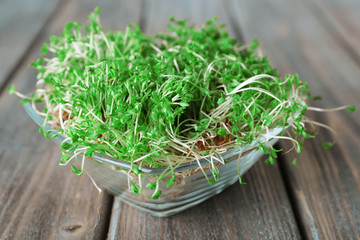 Fresh cress salad in glass bowl and wooden planks background