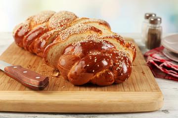 Sliced fresh bun on cutting board on bright background