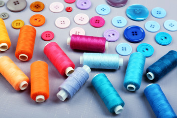 Colorful buttons and sewing threads on wooden background