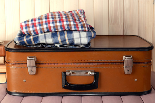 Vintage suitcase with clothes on wooden background