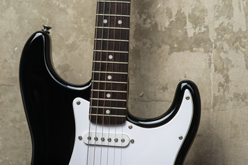 Obraz premium Black and white electric guitar near the concrete wall