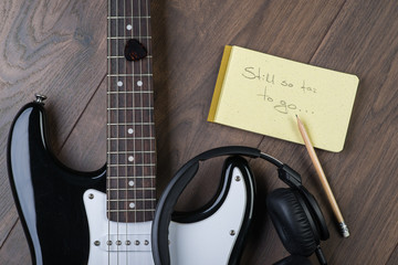 Black and white electric guitar on the wooden floor with notepad