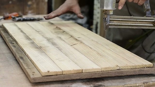 Carpenter shoot nail gun on wood planks