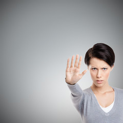 Smart girl shows stop gesture, isolated on grey background