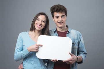 Smiling teenager couple with sign