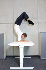 flexible business man in scorpion asana on desk in his office