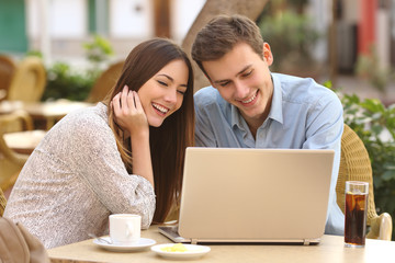 Couple watching media in a laptop in a restaurant