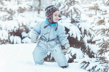 Fototapeta na wymiar little boy playing in a snowy forest