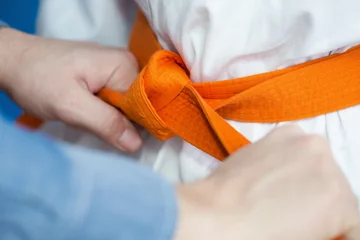 Crédence de cuisine en verre imprimé Arts martiaux Le père attache une ceinture orange sur l& 39 uniforme d& 39 arts martiaux de son fils
