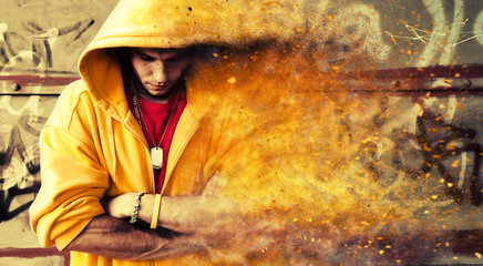 Young man in hooded sweatshirt on grunge wall. Particles effect