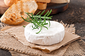 Camembert cheese and a sprig of rosemary on a wooden table