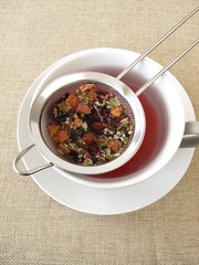 Kräutertee mit Früchten und Blüten im Teesieb