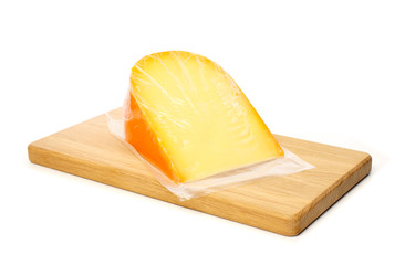 Cheese in vacuum packing on cutting board