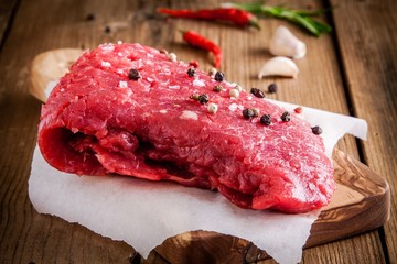 raw meat steak on a cutting board with garlic and pepper