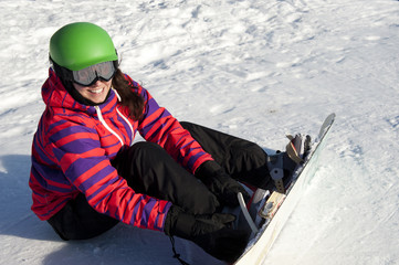 young woman putting on a snowboard