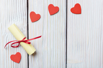 Red hearts and rolled paper on vintage wooden background