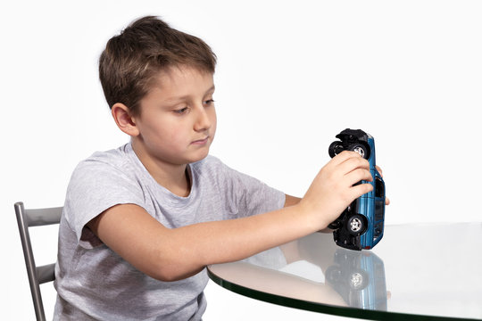 Boy playing with blue car on a glass table