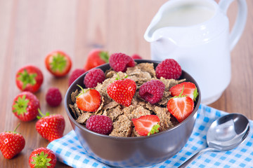 Bran flakes with fresh raspberries and strawberries and pitcher