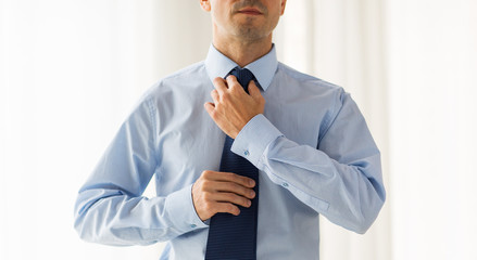 close up of man in shirt adjusting tie on neck