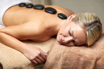 Obraz na płótnie Canvas close up of woman having hot stone massage in spa