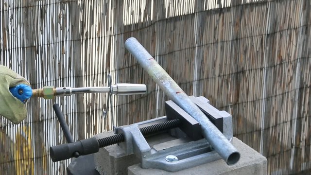 Gasbrenner erhitzt Eisenrohr im Schraubstock