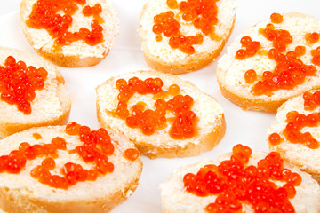 Red caviar on bread with butter on white plate closeup
