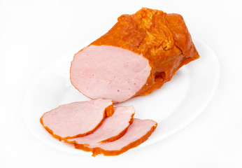 Large piece of ham with cut slices on plate, isolated on white b