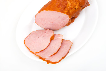 Large piece of ham with cut slices on plate, isolated on white b