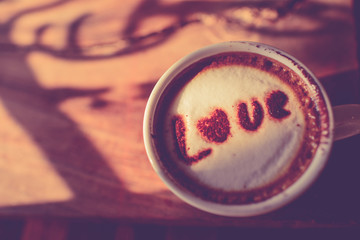 Love message on coffee cup on wooden background with vintage col