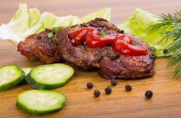 tasty grill meat with sauce and green on wooden background