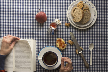 woman having breakfast, his hands and a book