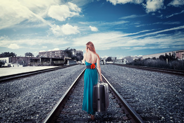Young woman walking away on rail tracks talking on phone