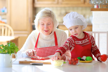 Grandmother making pizza with her granddaughter