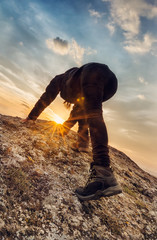 Young woman climbs a rocky hill