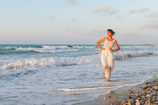 Young woman enjoys a lonesome walk on the beach at dusk.