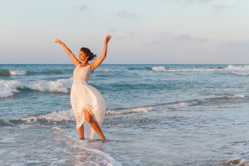 Young woman enjoys a lonesome walk on the beach at dusk.