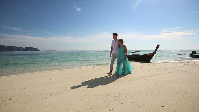 asian blonde girl and boyfriend walk on sandy beach	