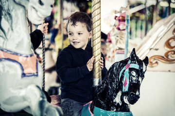 Fototapeta na wymiar Happy Boy on a Carousel Horse Ride - Retro Filtered