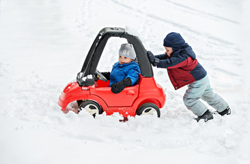 Young Boy Gives a Push to his Brother's Car Stuck in the Snow - 78137348