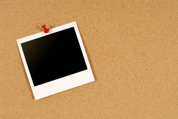 Single blank polaroid style photo print frame pinned to a cork notice or bulletin board